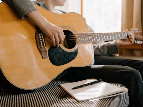 Un adulte apprend un accord sur une guitare acoustique